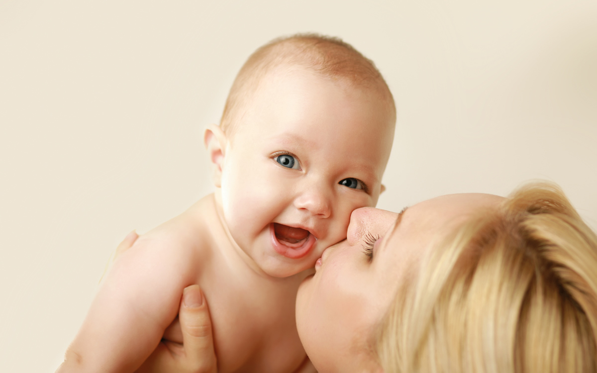 mum is kissing her happy baby